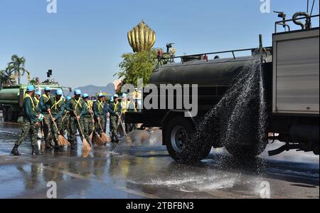 De jeunes représentants de l'armée royale thaïlandaise aident les autres lors d'une journée nationale de nettoyage à Nakhon Phanom, en Thaïlande, en Asie du Sud-est. Le 5 décembre est une fête nationale car il commémore l'anniversaire du défunt roi Bhumibol Adulyadej, Rama 9. Cet événement commence par des participants en uniforme qui défilent pour des photos et de courts discours, suivis par tous ceux qui utilisent des brosses brindilles et des camions-citernes pour nettoyer les rues. Cette journée est connue sous le nom de fête des pères en Thaïlande. Banque D'Images