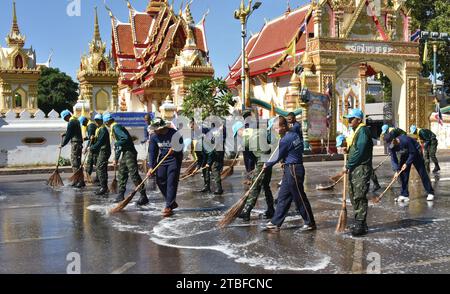 De jeunes représentants de l'armée royale thaïlandaise aident les autres lors d'une journée nationale de nettoyage à Nakhon Phanom, en Thaïlande, en Asie du Sud-est. Le 5 décembre est une fête nationale car il commémore l'anniversaire du défunt roi Bhumibol Adulyadej, Rama 9. Cet événement commence par des participants en uniforme qui défilent pour des photos et de courts discours, suivis par tous ceux qui utilisent des brosses brindilles et des camions-citernes pour nettoyer les rues. Cette journée est connue sous le nom de fête des pères en Thaïlande. Banque D'Images