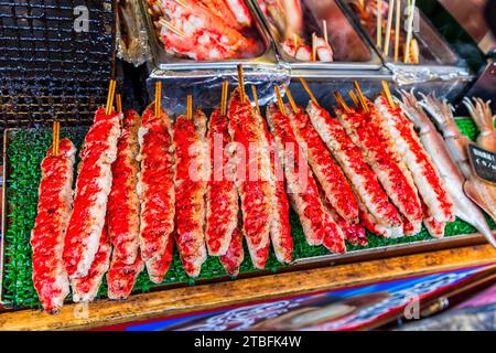 Stalle de nourriture de rue avec de la chair de crabe de fruits de mer cuite sur des brochettes au japon dans la rue commerçante touristique populaire de la ville de Kyoto. Banque D'Images