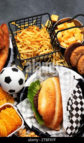 Graisses saturées. L'heure du football. Télécommande TV et collations - chips, pop-corn, biscuits, fromage, sauce, frites, burger, noix. Vue de dessus Banque D'Images