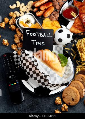 Graisses saturées. L'heure du football. Télécommande TV et collations - chips, pop-corn, biscuits, fromage, sauce, frites, burger, noix. Vue de dessus Banque D'Images