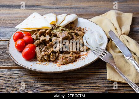 Viande en cubes, viande cuite sur plaque sur fond de bois avec légumes et épices. Banque D'Images