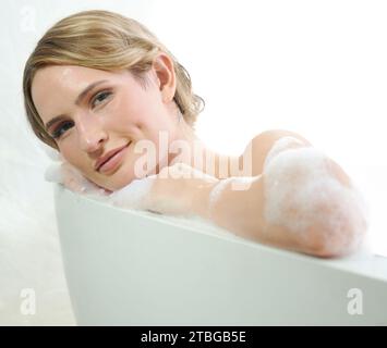 Femme, matin et bain moussant en portrait, hygiène relaxante et nettoyante avec beauté. Soins de la peau, bien-être et dermatologie avec visage, modèle féminin et Banque D'Images