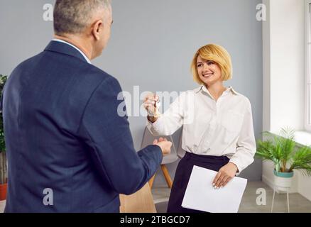 Agent immobilier femme souriante donne les clés à un heureux propriétaire de maison senior homme Banque D'Images