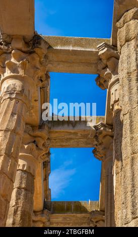 Vue de dessous des colonnes en granite du temple romain de Diane avec une colombe perchée sur ses poutres, sous un ciel bleu clair de midi. Merida, Espagne Banque D'Images