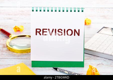 Le texte DE RÉVISION sur la feuille blanche du carnet est à côté d'une loupe, d'une calculatrice, d'un crayon, d'autocollants Banque D'Images