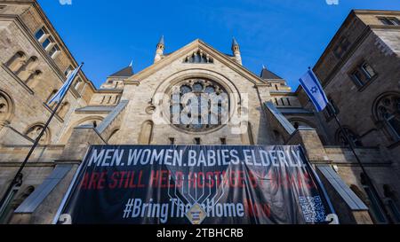 Cologne, Allemagne. 07 décembre 2023. Une bannière avec l'inscription 'Men. Femmes. Bébés. Personnes âgées. Sont toujours pris en otage par les stands du Hamas devant un candélabre Hanukkah devant la synagogue. Hanukkah, qui commence aujourd'hui, est une fête juive annuelle qui dure huit jours. Crédit : Rolf Vennenbernd/dpa/Alamy Live News Banque D'Images