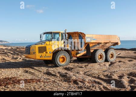 Un camion à benne basculante Volvo A35E réparant les défenses contre les inondations sur la plage de Hythe, Kent. Banque D'Images
