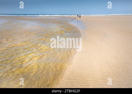 Les gens qui marchent le long de la rivière Menalhyl qui traverse la plage à Mawgan Porth, dans les Cornouailles, au Royaume-Uni. Banque D'Images