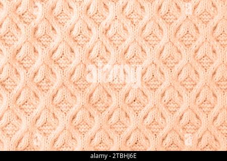 Démonstration des couleurs de 2024 - Peach Fuzz. Fond de pêche tricoté. Grand tissu tricoté avec un motif. Gros plan d'une couverture tricotée. Banque D'Images