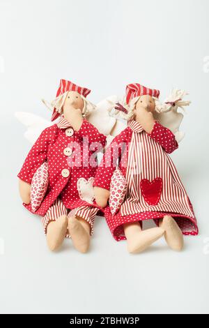 Deux poupée homme et femme en pyjama rouge robe tenant oreiller et bâillant sur fond blanc Banque D'Images