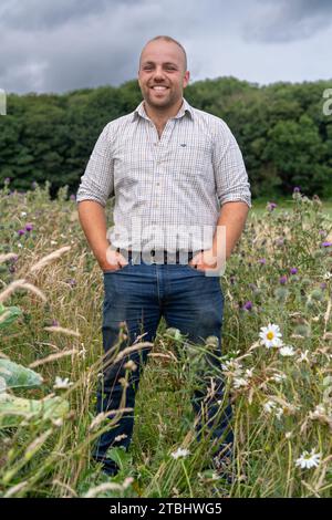 Agriculteur dans une bande de pollinisateurs de fleurs sur le bord de son champ qui est cultivé pour encourager les insectes et la faune. Co Durham, Royaume-Uni. Banque D'Images