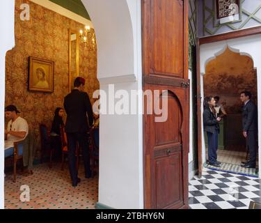 Café Bacha à l'intérieur du palais de Dar el Bacha. Les gestionnaires discutent en tant que travailleur à Fès Hat sert. Marrakech alias Marrakech, Maroc, 07 décembre 2023 Banque D'Images
