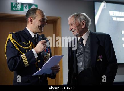 Le colonel français Xavier Ravel (à gauche) surprend David Morgan, 100 ans, vétéran de la Seconde Guerre mondiale, alors qu'il lui présente la Légion d'honneur pour sa participation aux opérations du jour J, lors de la fête de Noël taxi Charity for Military Veterans au Millwall football Club de Londres. Date de la photo : jeudi 7 décembre 2023. Banque D'Images