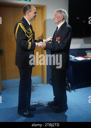 Le colonel français Xavier Ravel (à gauche) surprend David Morgan, 100 ans, vétéran de la Seconde Guerre mondiale, alors qu'il lui présente la Légion d'honneur pour sa participation aux opérations du jour J, lors de la fête de Noël taxi Charity for Military Veterans au Millwall football Club de Londres. Date de la photo : jeudi 7 décembre 2023. Banque D'Images