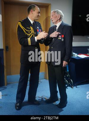 Le colonel français Xavier Ravel (à gauche) surprend David Morgan, 100 ans, vétéran de la Seconde Guerre mondiale, alors qu'il lui présente la Légion d'honneur pour sa participation aux opérations du jour J, lors de la fête de Noël taxi Charity for Military Veterans au Millwall football Club de Londres. Date de la photo : jeudi 7 décembre 2023. Banque D'Images