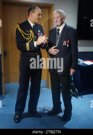 Le colonel français Xavier Ravel (à gauche) surprend David Morgan, 100 ans, vétéran de la Seconde Guerre mondiale, alors qu'il lui présente la Légion d'honneur pour sa participation aux opérations du jour J, lors de la fête de Noël taxi Charity for Military Veterans au Millwall football Club de Londres. Date de la photo : jeudi 7 décembre 2023. Banque D'Images