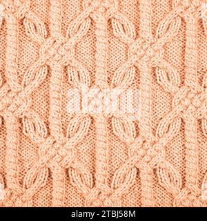 Fond de pêche tricoté. Grand tissu tricoté avec un motif. Gros plan d'une couverture tricotée. Démonstration des couleurs de 2024 - Peach Fuzz. Banque D'Images