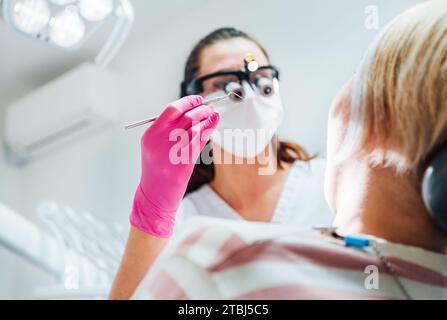 Médecin dentiste en loupes avec outil Dental explorer. Jeune femme prête pour la chirurgie dentaire. Rendez-vous en clinique dentaire dans le medi moderne Banque D'Images
