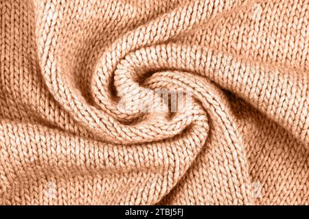 Démonstration des couleurs de 2024 - Peach Fuzz. Fond de pêche tricoté. Grand tissu tricoté avec un motif. Gros plan d'une couverture tricotée. Banque D'Images