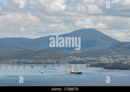 Hobart, Tasmanie, Australie - décembre 12 2022 : l'estuaire de Derwent avec un cargo et un remorqueur de boarts naviguant devant le pont de Derwent vers l'entrée de harb Banque D'Images