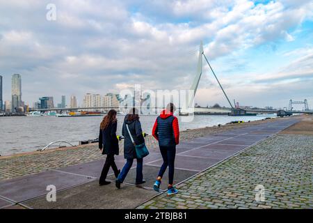 Rotterdam, pays-Bas - décembre 2 2023 : point de repère pittoresque du port de Rotterdam avec des gens marchant le long du quai devant le pont Erasmus et la ville Banque D'Images