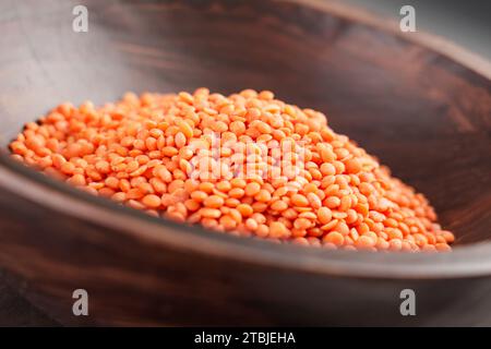 Bol en bois rustique avec grains de lentilles rouges biologiques crus. Produit céréalier à haute teneur en protéines. Grains d'orange crus. Banque D'Images