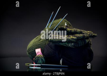 fil de laine, aiguilles à tricoter et autres outils pour tricoter à la main, isolé sur un fond noir. Banque D'Images