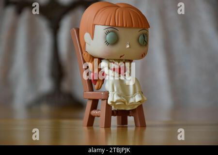 Funko Pop figurine d'action de poupée hantée Annabelle des films d'horreur surnaturels évoquant. Intérieur vintage, pièce sombre, vieux chandelier. Banque D'Images