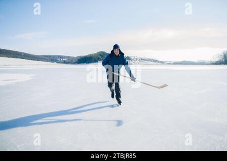 Homme âgé sur des patins à glace avec bâton de hockey sur le lac gelé en hiver. Le concept de hobby des personnes âgées. Banque D'Images