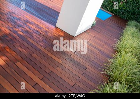 Terrasse en bois franc avec colonne carrée en béton, clôture à feuilles persistantes et piscine, terrasse en bois exotique idée Banque D'Images