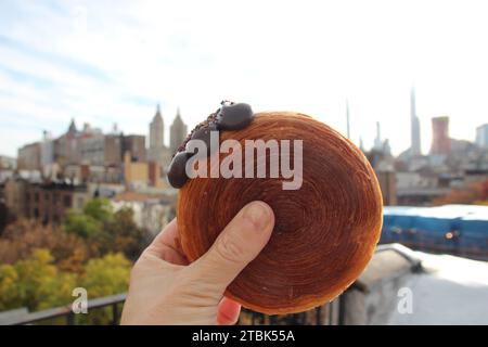 New York, États-Unis. 17 novembre 2023. Une femme tient un 'suprême' - une sorte de croissant fourré de crème au chocolat. (Pour dpa-KORR 'il y a dix ans, le 'cronutt' est devenu la mère des tendances alimentaires virales') crédit : Christina Horsten/dpa/Alamy Live News Banque D'Images