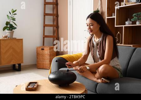 Jeune femme asiatique avec des bâtons jouant du glucophone à la maison Banque D'Images