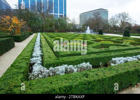 Superbe jardin botanique dans le centre-ville de Bruxelles à la fin de l'automne avec des buissons topiaires (buis) et fontaine et ville en arrière-plan Banque D'Images