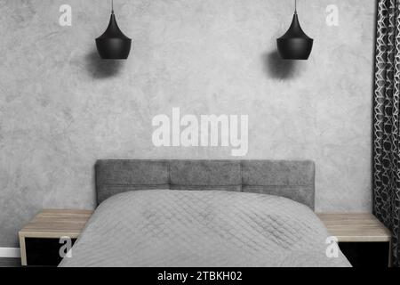 Design moderne de la chambre dans les tons gris, minimalisme dans l'intérieur. Grand lit dans la chambre, tables de chevet en verre noir, lustres noirs Banque D'Images