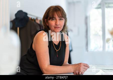 Créatrice de mode féminine regardant la caméra tout en se penchant sur son bureau dans son studio. Espace de copie Banque D'Images