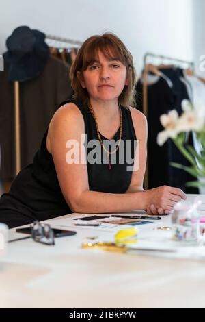 Créatrice de mode féminine regardant la caméra tout en se penchant sur son bureau dans son studio. Tir vertical Banque D'Images