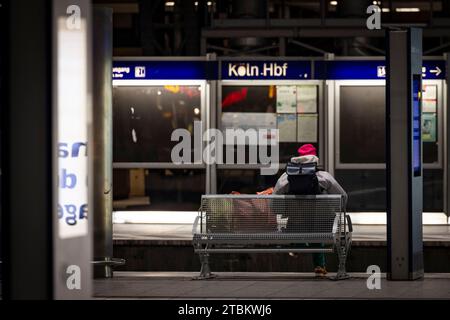 Cologne, Allemagne. 07 décembre 2023. Une femme avec des bagages est assise sur un banc sur une plate-forme et attend. Le syndicat allemand des conducteurs de train (GDL) a entamé une grève d'avertissement de 24 heures dans la soirée. Crédit : Christoph Reichwein/dpa/Alamy Live News Banque D'Images