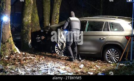 07 décembre 2023, Basse-Saxe, Ganderkesee : un policier se tient à côté d'un véhicule impliqué dans un accident. Un conducteur a heurté un arbre à Ganderkesee (district d'Oldenburg) jeudi soir et a été tué. Sa voiture avait déjà quitté la route de campagne, ont annoncé vendredi soir les pompiers. L'homme coincé dans la voiture a dû être libéré par les pompiers. Il est mort de ses blessures sur les lieux de l'accident. Sa passagère a pu laisser la voiture toute seule et a été emmenée à l'hôpital. Au départ, il n'était pas clair comment l'accident s'est produit. Photo : Nord-West-Media TV/dpa Banque D'Images