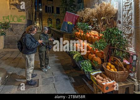 Touristes photographiant un magasin de fruits dans la soirée dans le centre historique, Gênes, Italie Banque D'Images