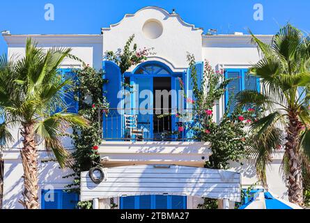 Maison blanche aux volets bleus, plantes tropicales et palmiers pittoresques. Une excellente destination de vacances sur la côte égéenne à Bodrum en Turquie Banque D'Images