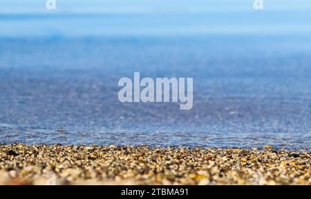 Un fond de sable, de petits cailloux et de vagues sur la plage de la mer. Vacances d'été et concept de nature côtière Banque D'Images