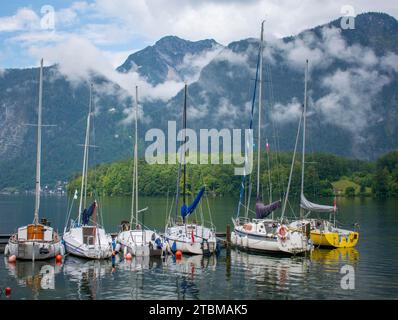 Ligne de petits bateaux amarrés au lac. Rangée des petits navires. Les Alpes autrichiennes en arrière-plan. Hallstatt. Autriche Banque D'Images