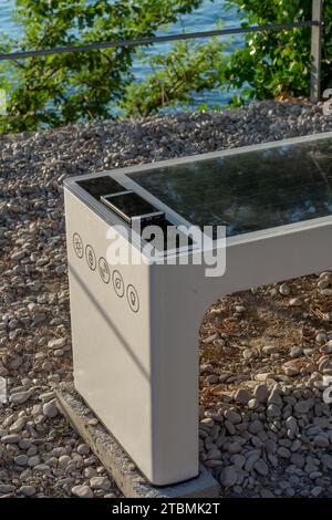 Smart Solar Bench dans les lieux publics, alimenté par la lumière du soleil fournit une charge sans fil et filaire pour les utilisateurs, wifi gratuit et capteurs de température et météo Banque D'Images