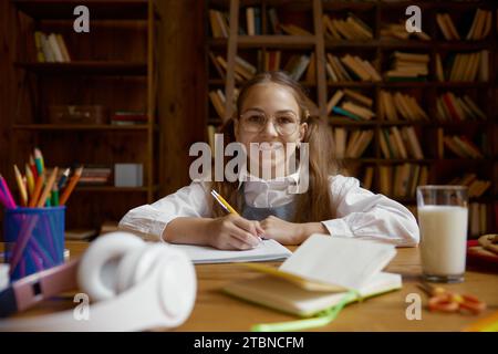 Portrait d'une écolière heureuse faisant ses devoirs ou étudiant à son bureau Banque D'Images