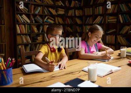Intelligent petit frère et sœur étudiant faire leurs devoirs ensemble à la maison Banque D'Images