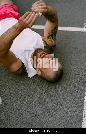 Un homme est allongé sur le sol après une compétition CrossFit. Banque D'Images