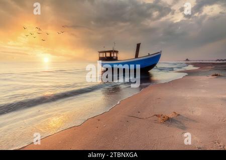 Vieux bateau de pêche en bois sur la plage de la mer Baltique sur l'île d'Usedom au lever du soleil Banque D'Images