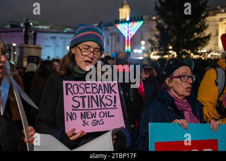 Un manifestant chante des chants de Noël tout en tenant une pancarte pendant la manifestation sur le Trafalgar Square à Londres. Les activistes de extinction Rebellion ont organisé une manifestation lors de la cérémonie officielle des lumières de Noël pour protester contre les plans d'Equinor, basé en Norvège, de développer le champ pétrolifère de Rosebank au Royaume-Uni. Banque D'Images