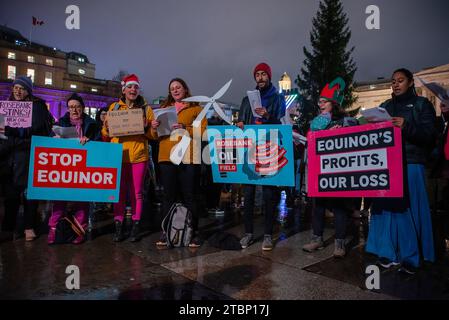 Les manifestants chantent des chants de Noël tout en brandissant des pancartes pendant la manifestation sur le Trafalgar Square à Londres. Les activistes de extinction Rebellion ont organisé une manifestation lors de la cérémonie officielle des lumières de Noël pour protester contre les plans d'Equinor, basé en Norvège, de développer le champ pétrolifère de Rosebank au Royaume-Uni. Banque D'Images